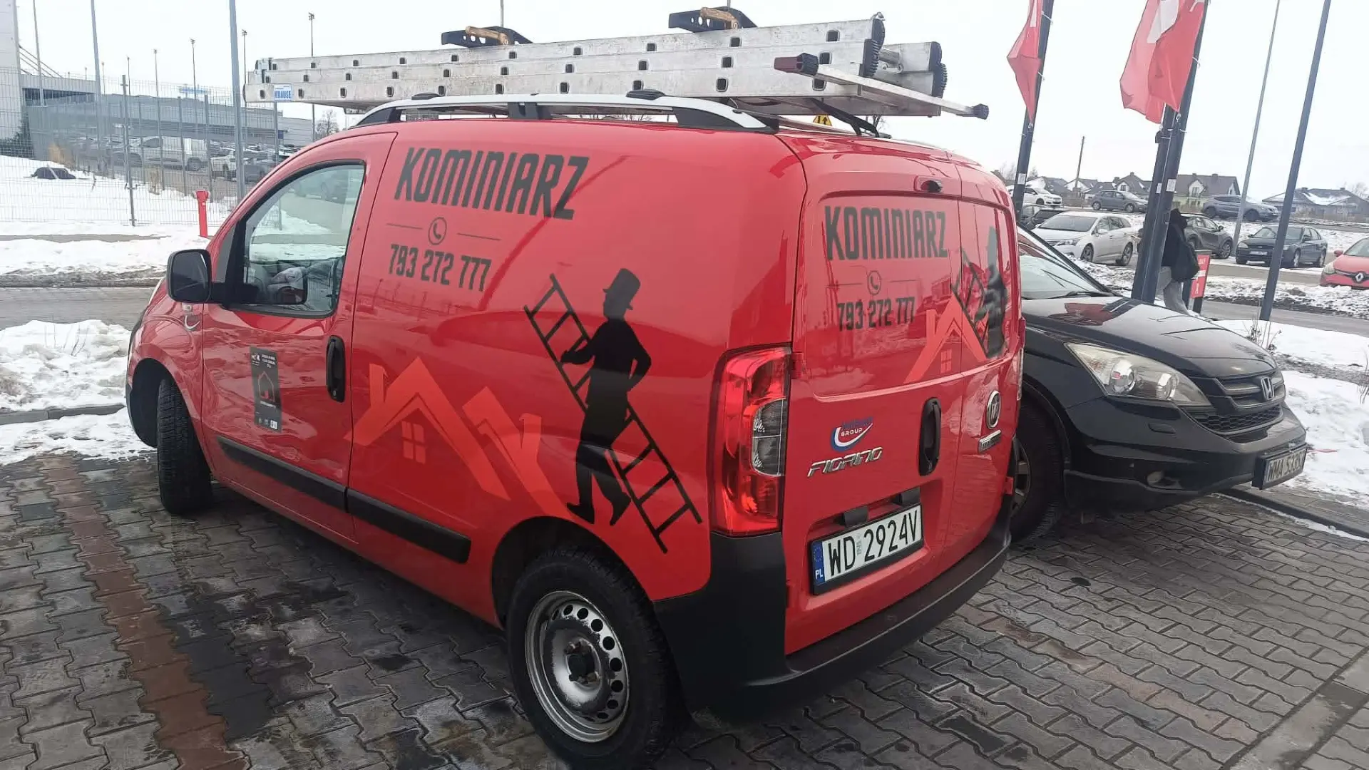 Oznakowany czerwony samochód firmowy zakładu kominiarskiego